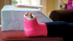 Christine, after her bone surgery, with foam wedge that she discovered for keeping her leg updated, and her medical record, printed in paper, on top (she is checking how much she was charged for it)