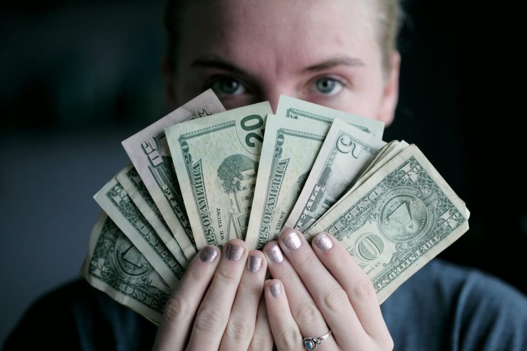 Girl holding cash on her hand in front of her face