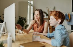 mother showing son info on desktop computer